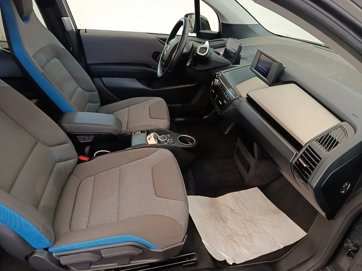 Vue intérieure côté conducteur de la BMW i3 120 Ah Atelier 2020, sièges gris avec surpiqûres bleues et tableau de bord moderne.