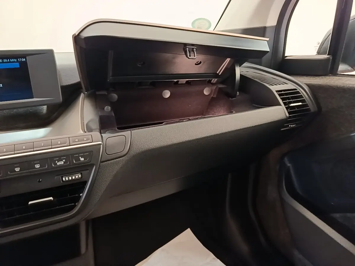 Intérieur de la BMW i3 120 Ah noir, vue côté passager avec boîte à gants ouverte et tableau de bord moderne.