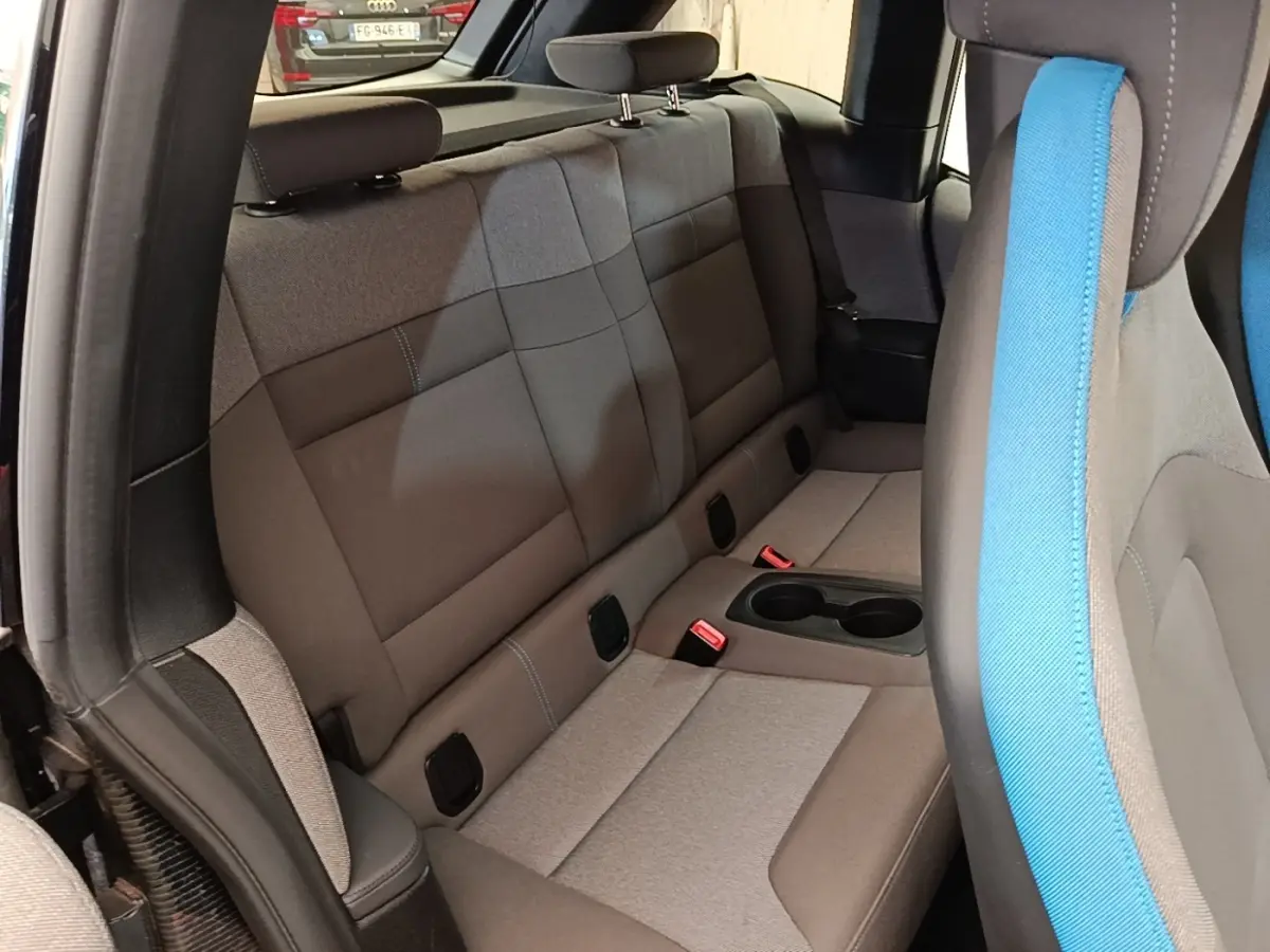 Vue intérieure côté arrière droit de la BMW i3 120 Ah noire, montrant la banquette arrière grise avec porte-gobelets central.