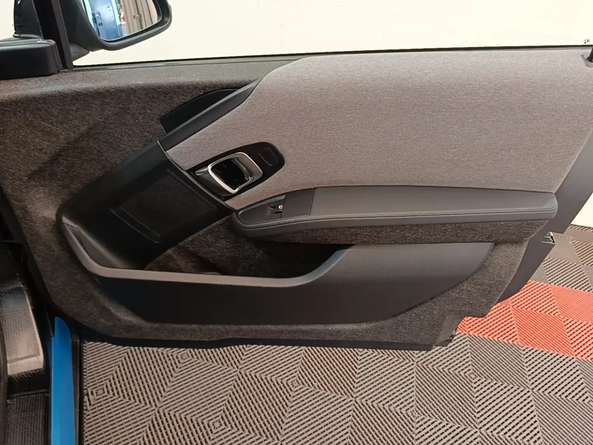 Vue intérieure de la porte côté gauche d'une BMW i3 120 Ah noire, avec habillage tissu gris et accoudoir noir.