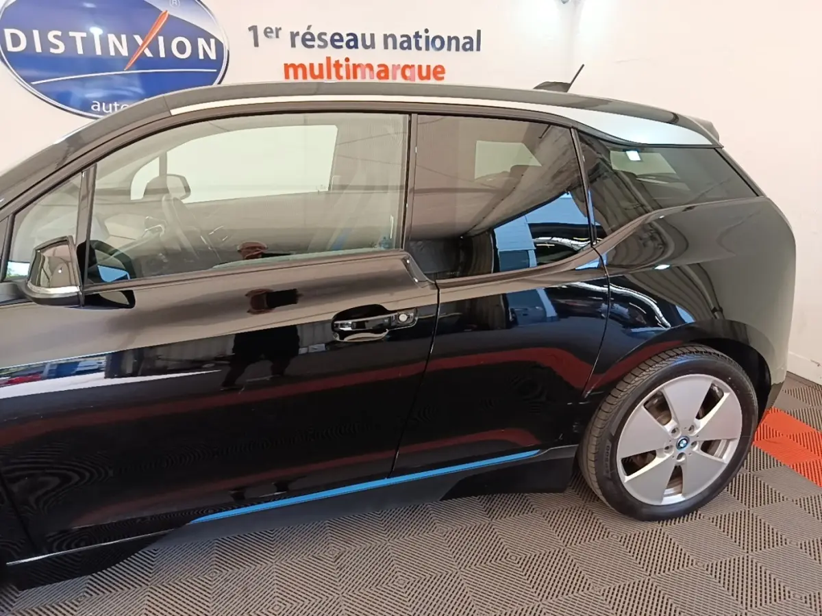 Profil côté droit d'une BMW i3 120 Ah noire, mettant en valeur sa silhouette compacte et ses jantes distinctives.