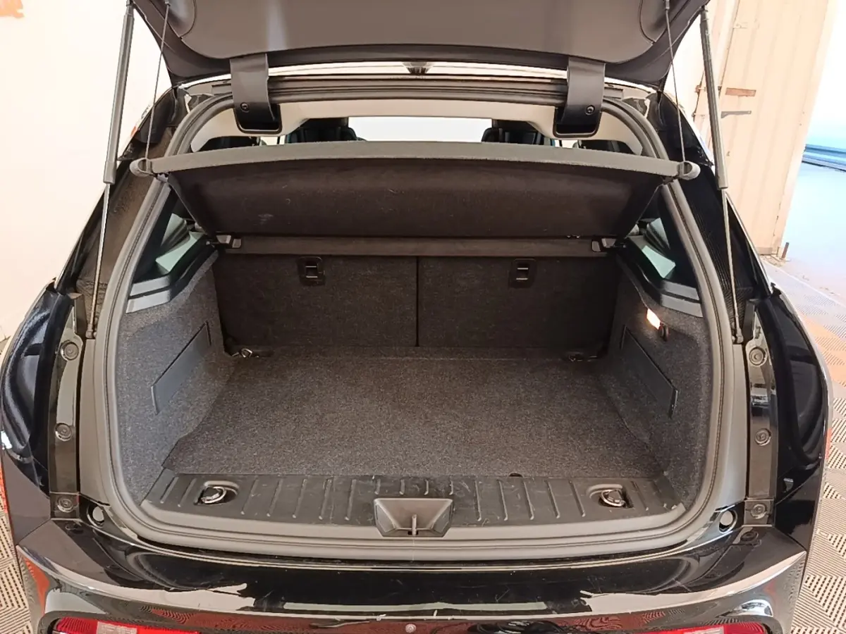 Coffre ouvert d’une BMW i3 120 Ah noire vue de l’arrière, montrant l’espace de chargement et la tablette de séparation.