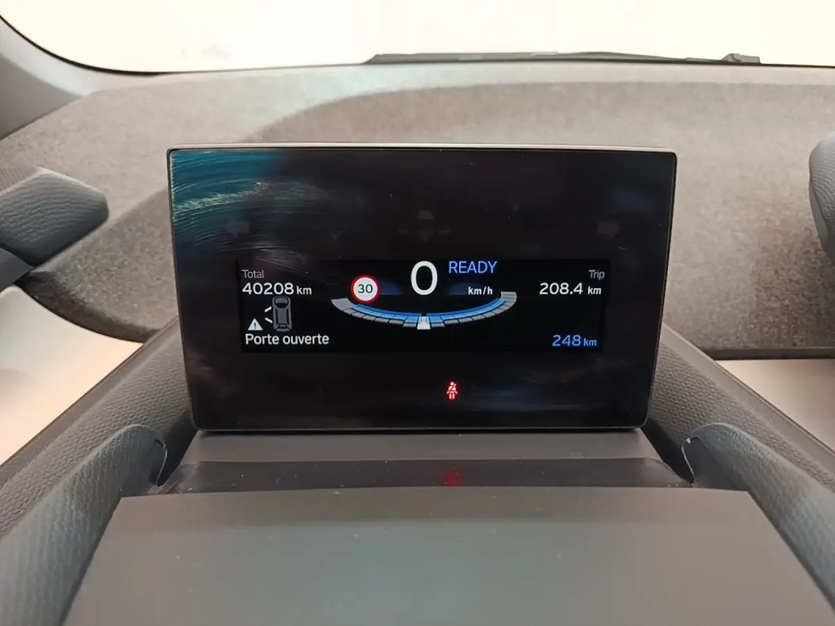 Affichage numérique du tableau de bord de la BMW i3 120 Ah Atelier montrant vitesse, autonomie et porte ouverte.