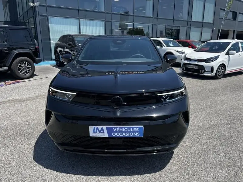 Vue avant d’un Opel Mokka Electric 156 GS noir 2025, avec calandre épurée et phares LED fins, sur parking extérieur.