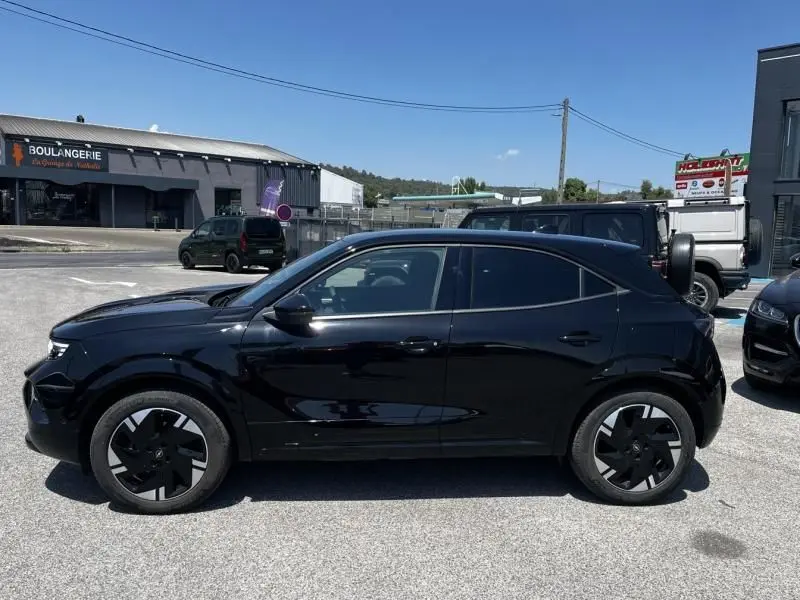 Vue de profil côté gauche d'un Opel Mokka Electric 156 GS noir 2025 garé en extérieur sous un ciel bleu.