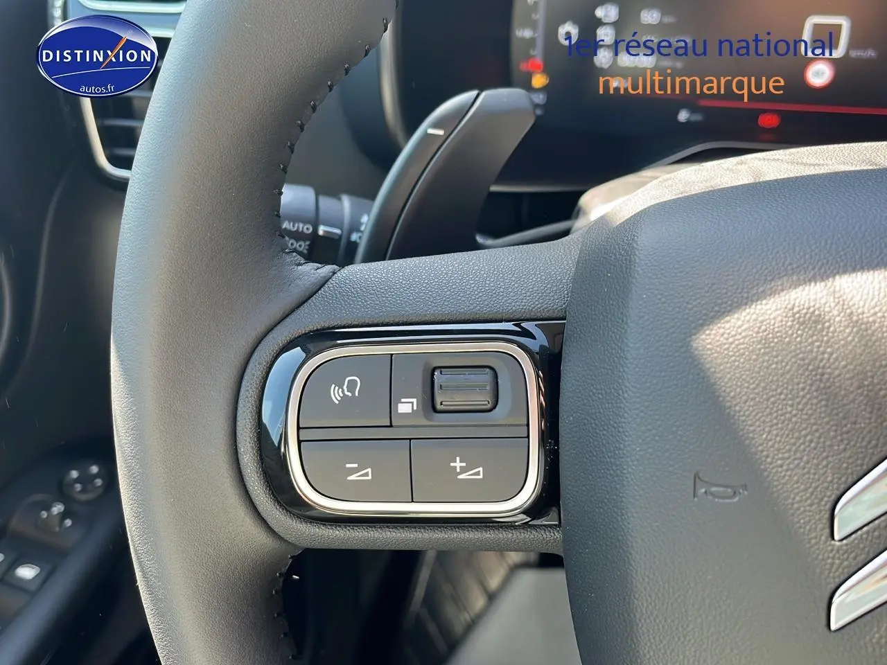 Gros plan sur les commandes gauche du volant du Citroën C5 Aircross 2025 noir, avec tableau de bord digital en arrière-plan.