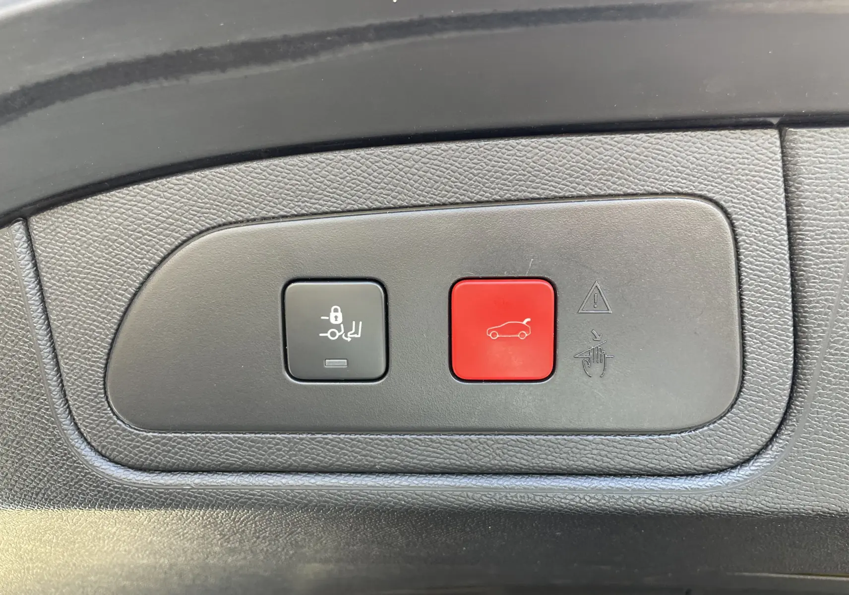 Gros plan sur les boutons de commande de coffre, noir et rouge, dans l'habitacle d'un DS7 gris Artens 2018.