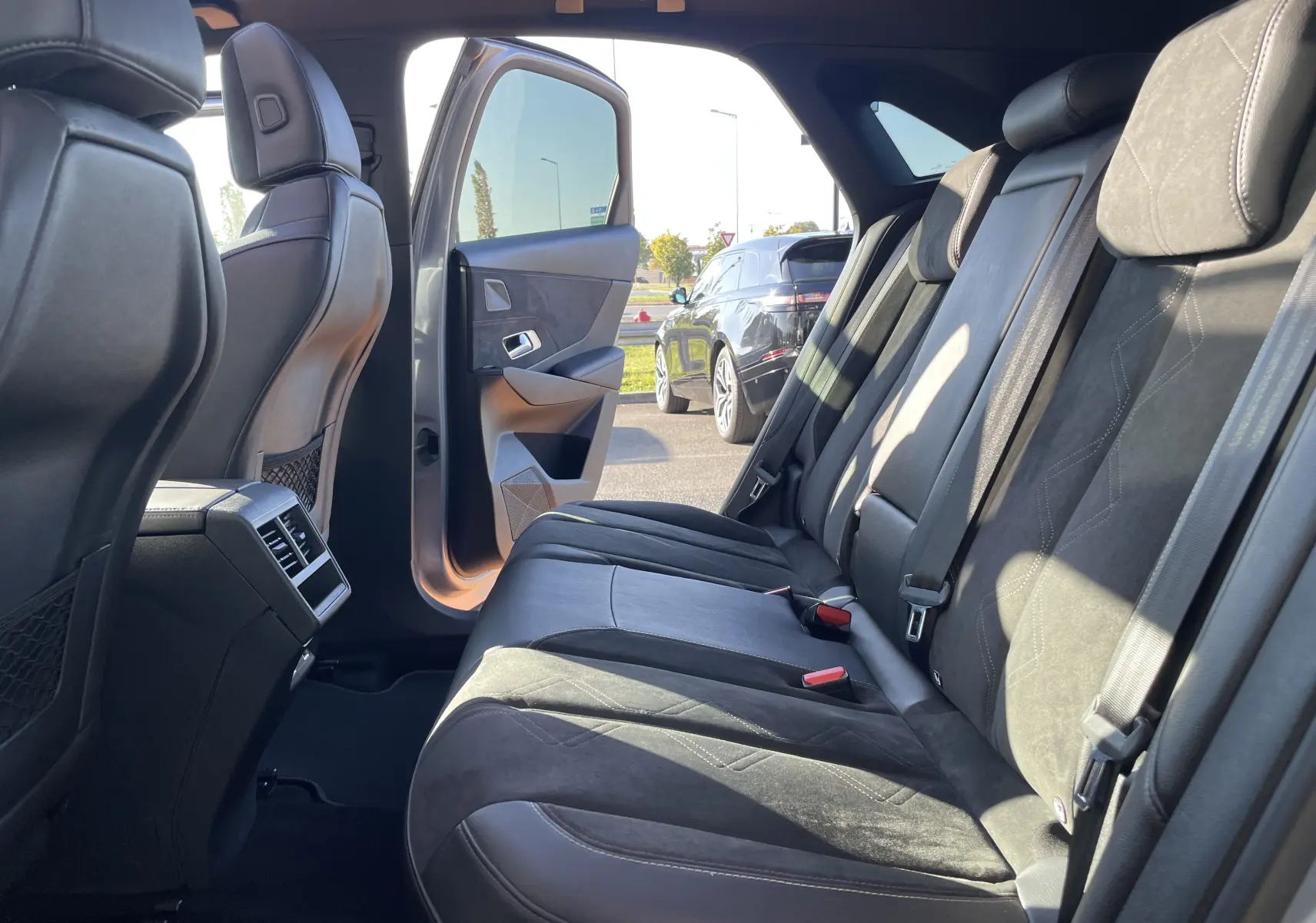 Vue intérieure côté droit des sièges arrière en cuir noir du DS7 gris, porte arrière ouverte laissant entrer la lumière naturelle.