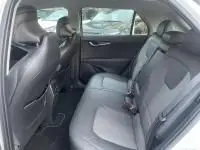 Intérieur arrière du Kia Niro EV 204 CV Active 2024 blanc, montrant les sièges arrière en tissu gris et les portières.