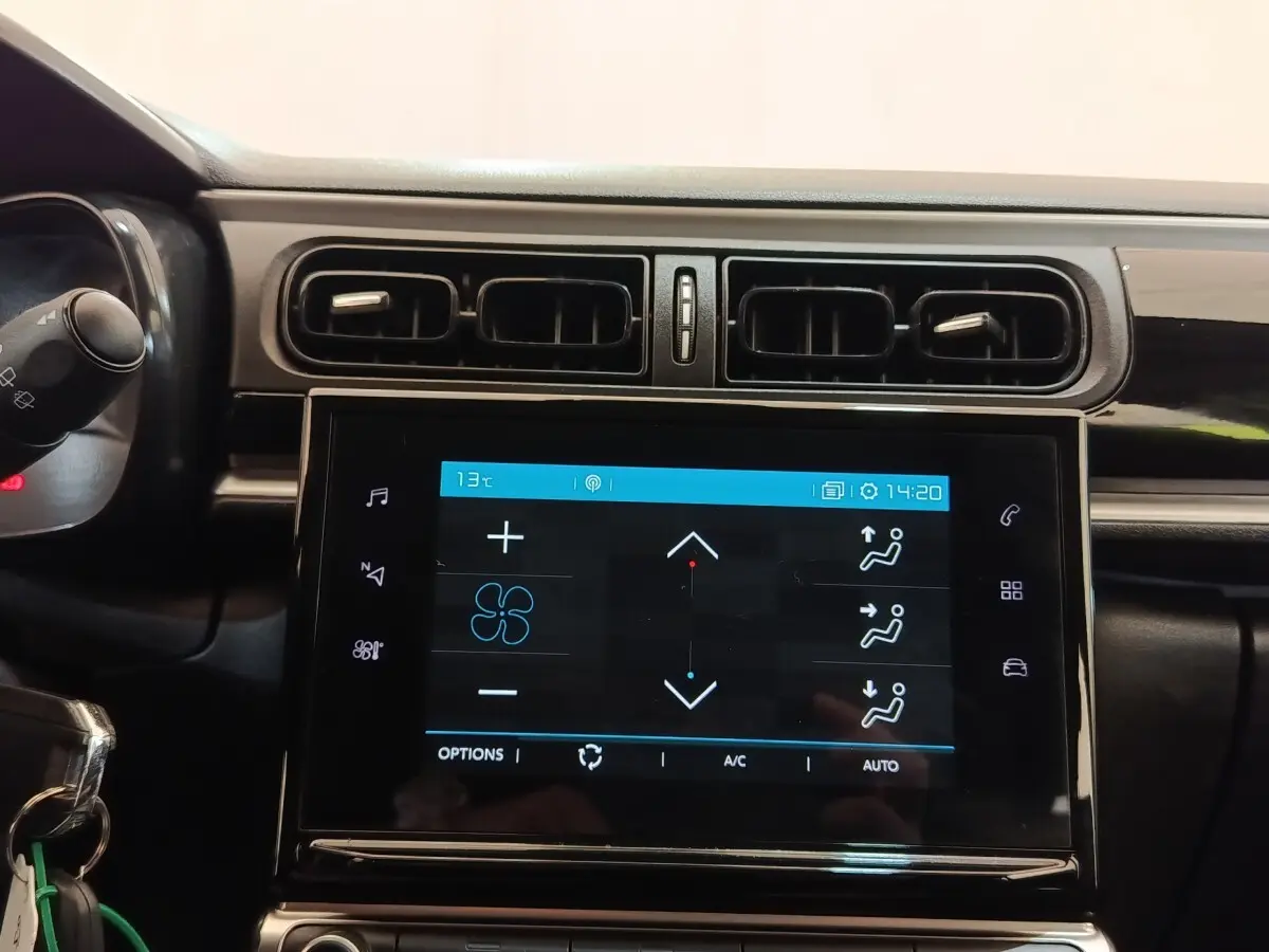 Écran tactile central noir affichant la climatisation, entouré des aérateurs horizontaux du tableau de bord d'une Citroën C3.