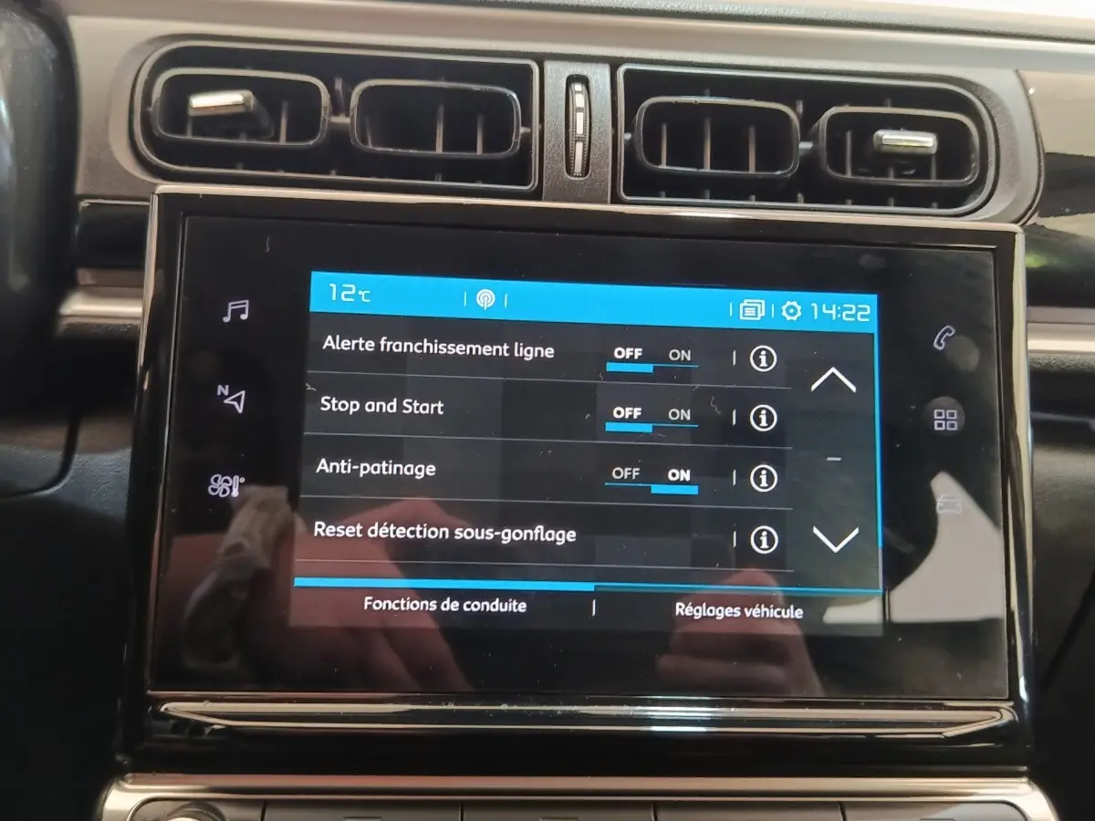 Écran tactile central de la Citroën C3 blanche, vue rapprochée du tableau de bord avec réglages affichés.