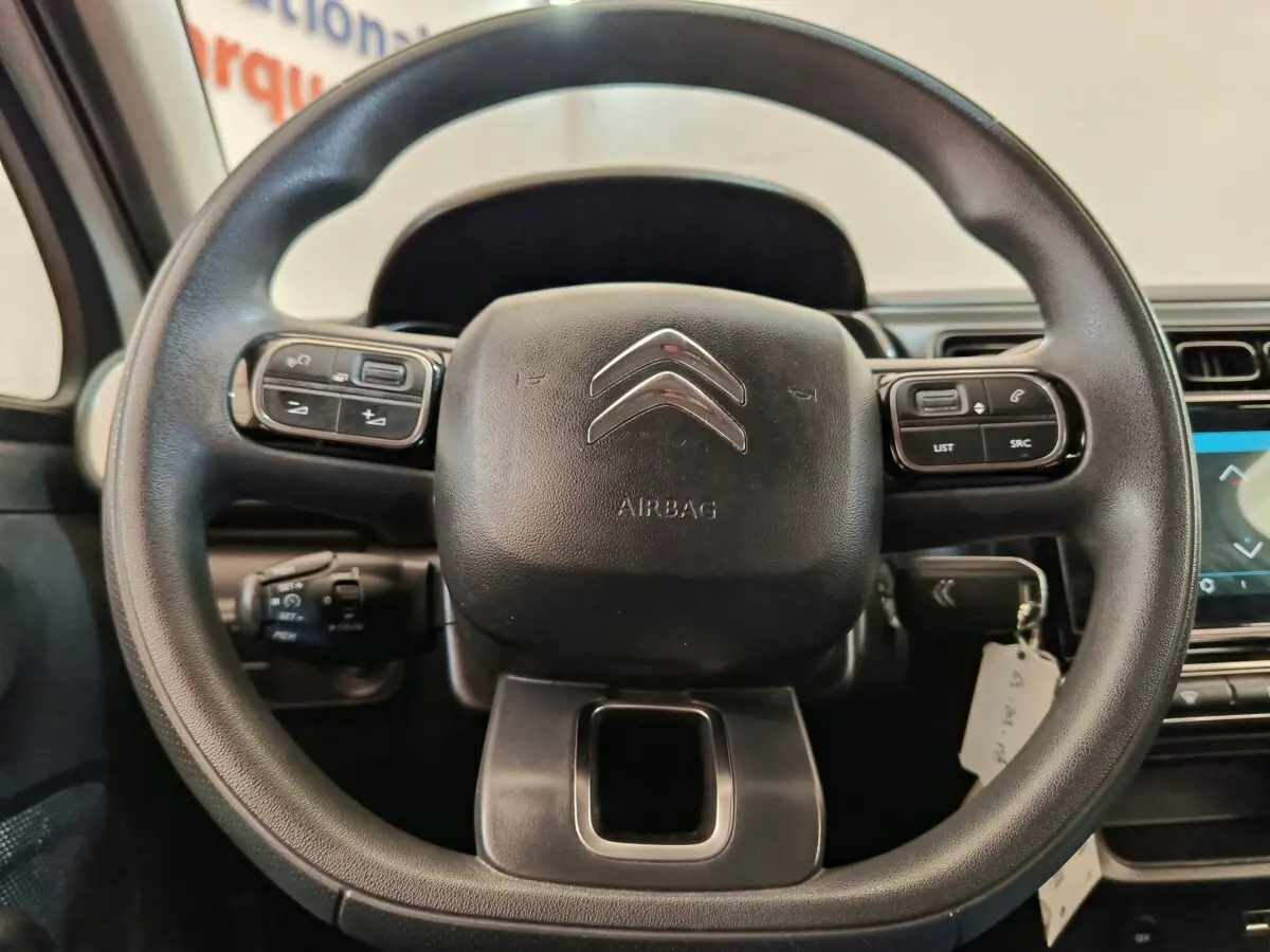 Vue rapprochée du volant multifonctions noir de la Citroën C3 2022 avec commandes intégrées et logo chrome central.
