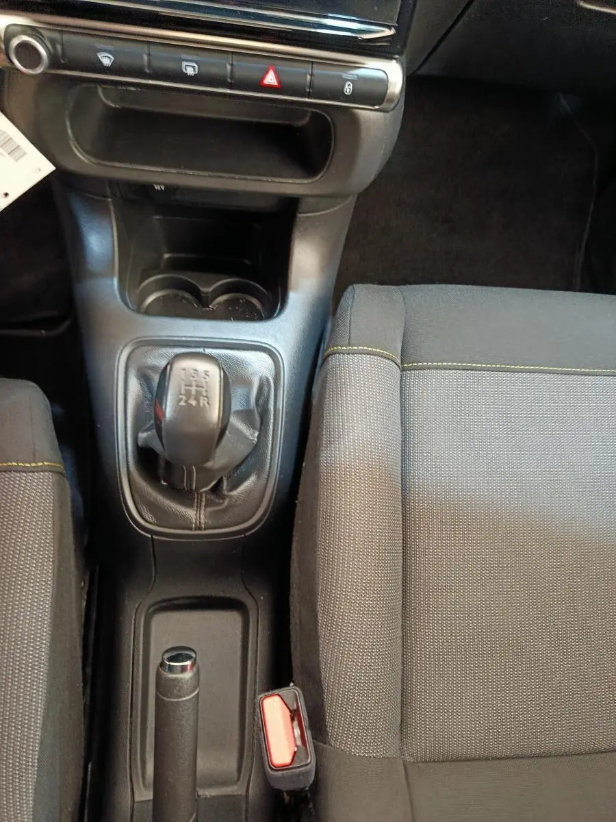 Vue intérieure centrée sur la console centrale et levier de vitesses manuelle d'une Citroën C3 2022 avec sièges gris.