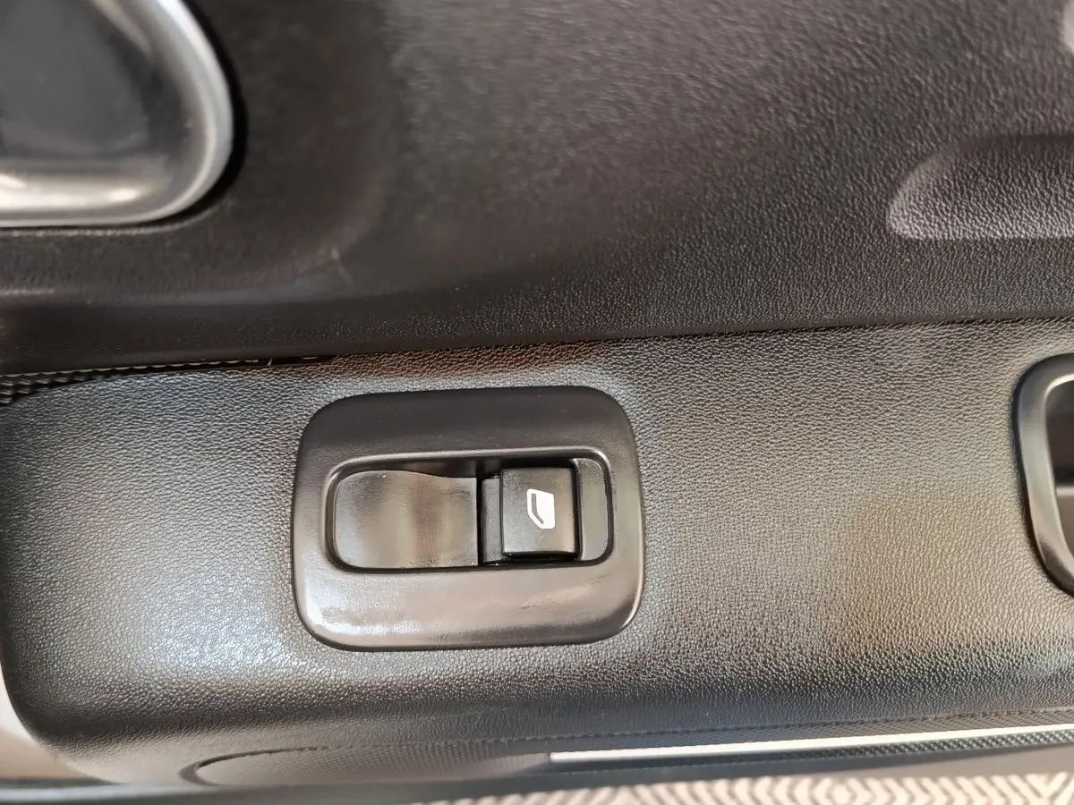 Gros plan sur le bouton de commande de lève-vitre côté conducteur de la Citroën C3 blanche, intérieur noir.