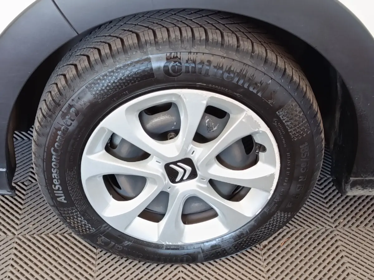 Gros plan sur la roue avant gauche d'une Citroën C3 blanche avec jante en alliage et logo Citroën central.