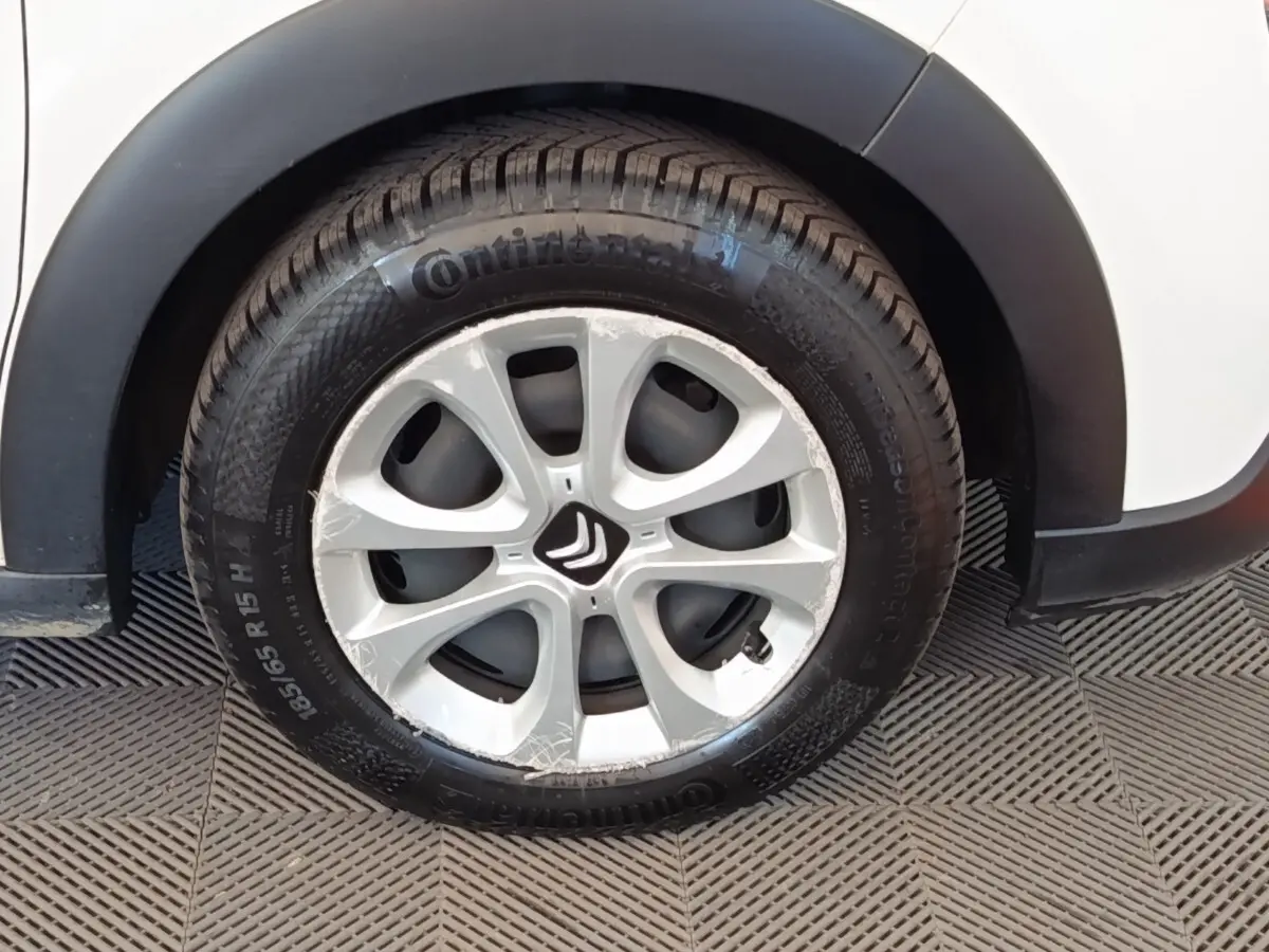 Gros plan sur la roue avant droite d'une Citroën C3 blanche avec jante argentée et logo Citroën au centre.
