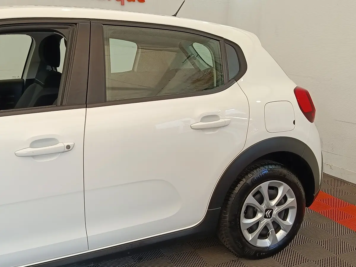 Vue latérale côté gauche d'une Citroën C3 blanche, mettant en valeur les poignées de porte et la roue arrière.