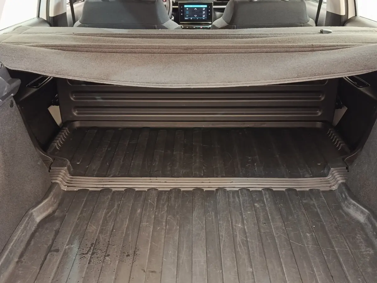 Vue du coffre ouvert d'une Citroën C3 blanche 2022, avec plancher caoutchouté et tablette arrière relevée.