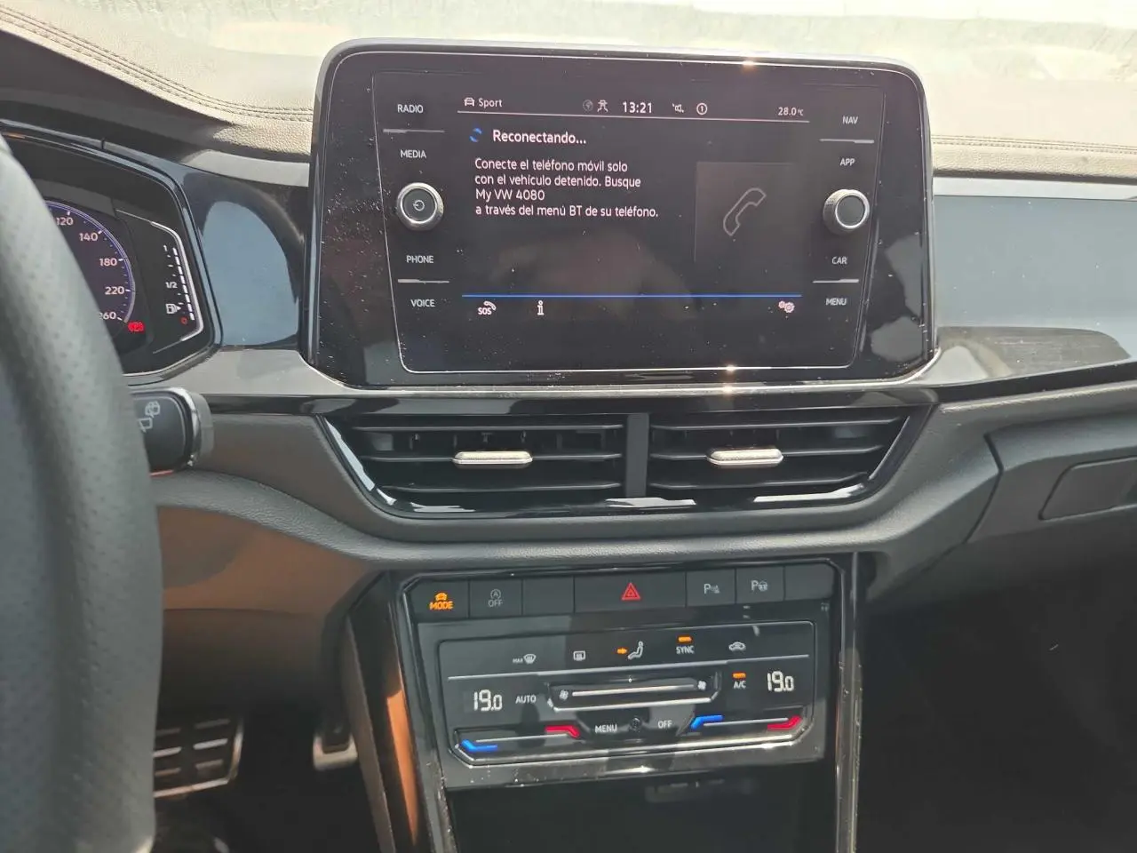Vue rapprochée du tableau de bord noir brillant du Volkswagen T-Roc 2025 avec écran tactile et commandes climatisation digitales.
