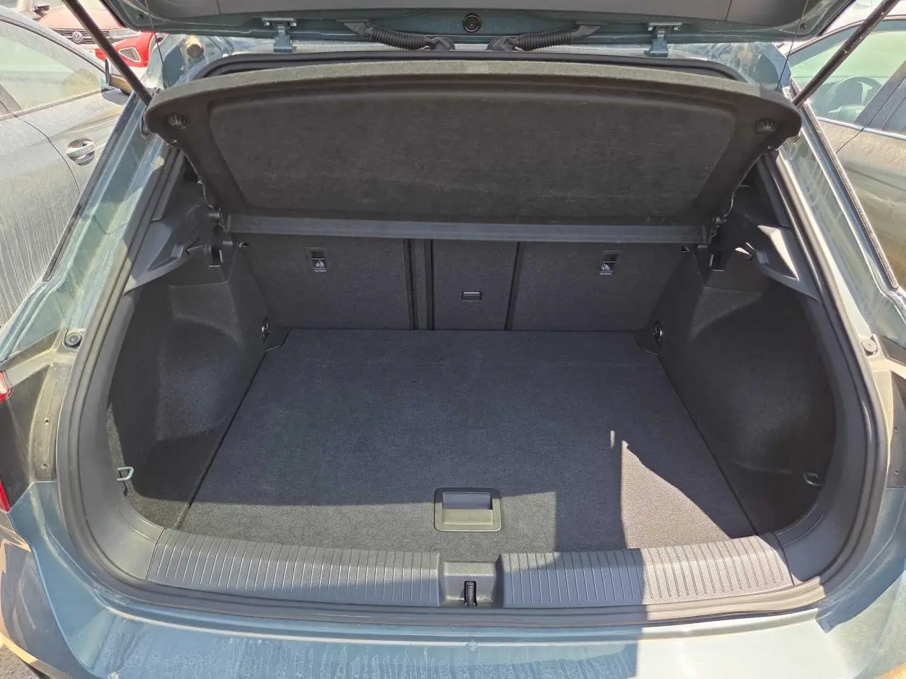 Coffre ouvert vu de l'arrière d'un Volkswagen T-Roc noir métal, montrant un espace de chargement vide et propre.