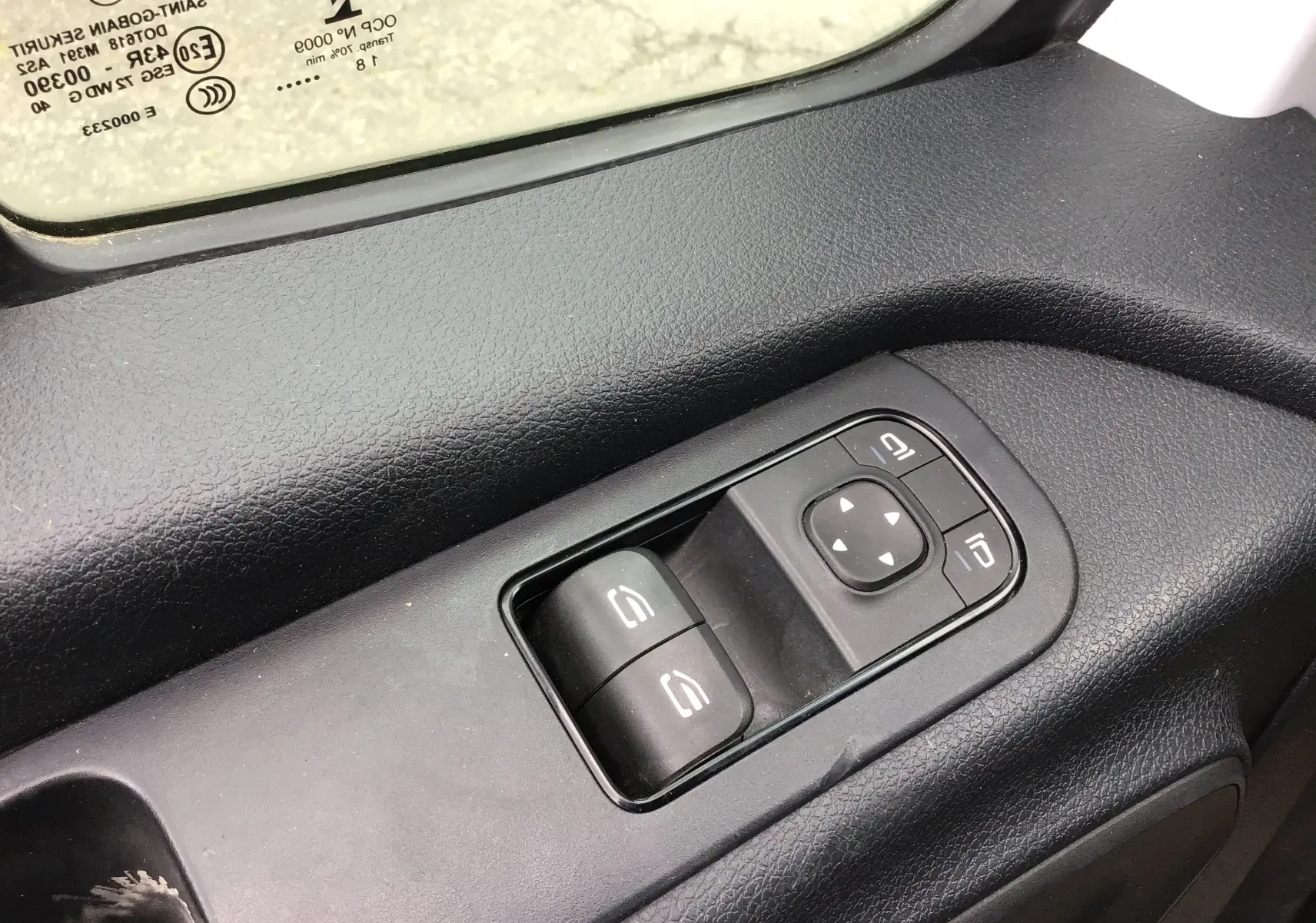 Gros plan sur les commandes électriques des vitres côté conducteur d'un Mercedes Sprinter blanc, intérieur noir.