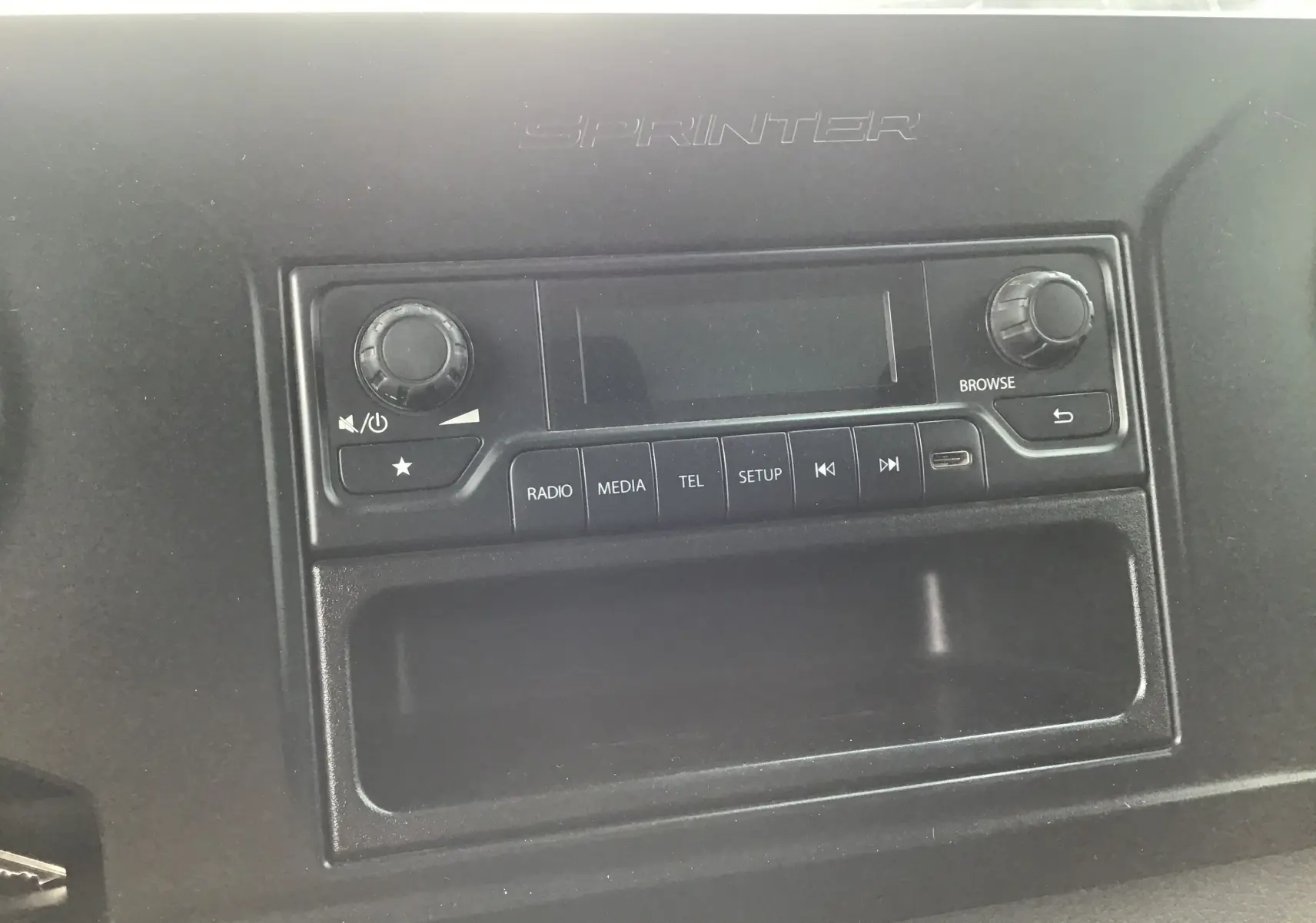 Vue rapprochée de la console centrale noire du Mercedes Sprinter 514 CDI avec commandes radio et inscription Sprinter.