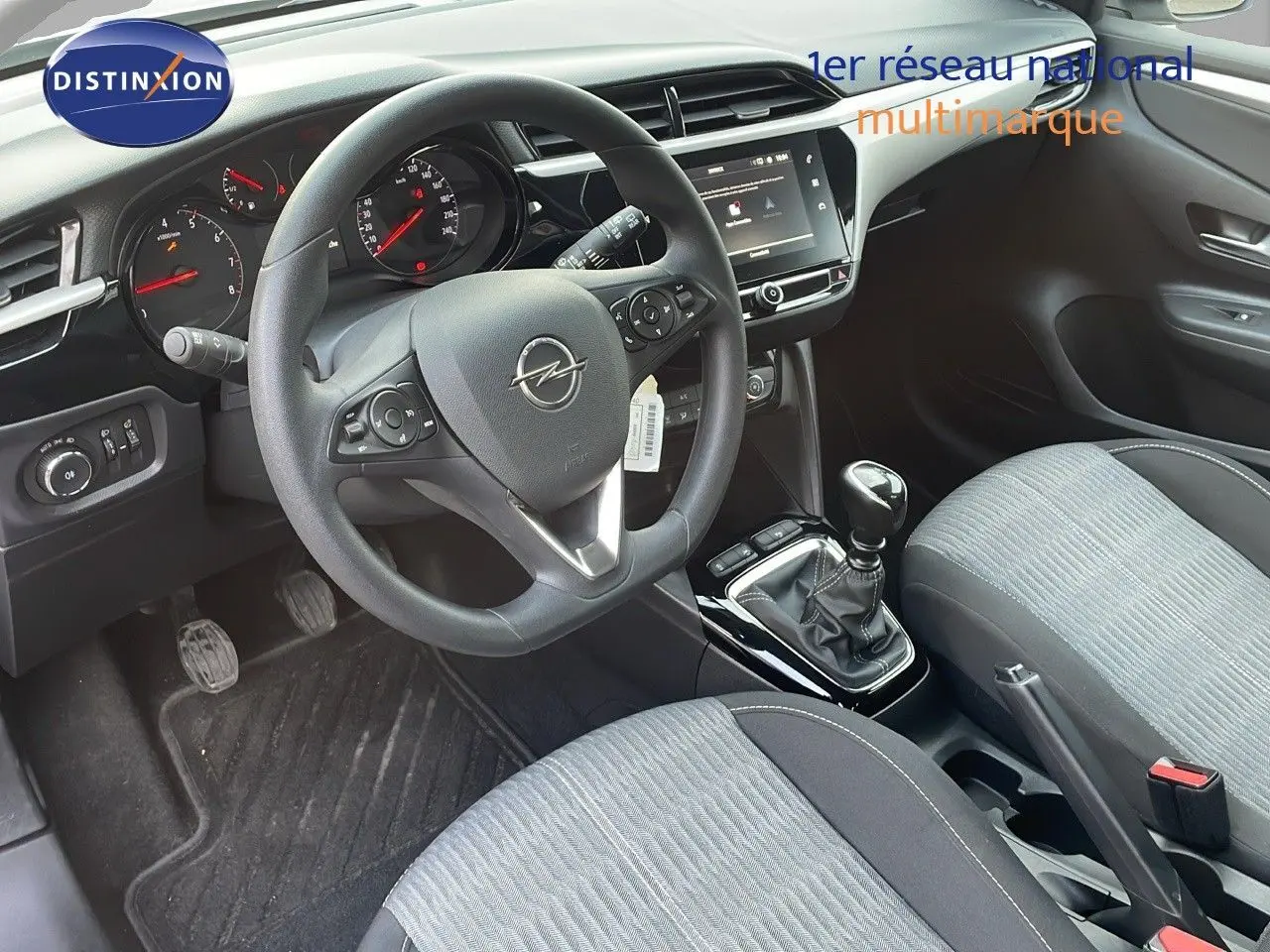 Vue intérieure côté conducteur de l'Opel Corsa gris Kristall Metal, volant multifonction et levier de vitesse manuel visibles.