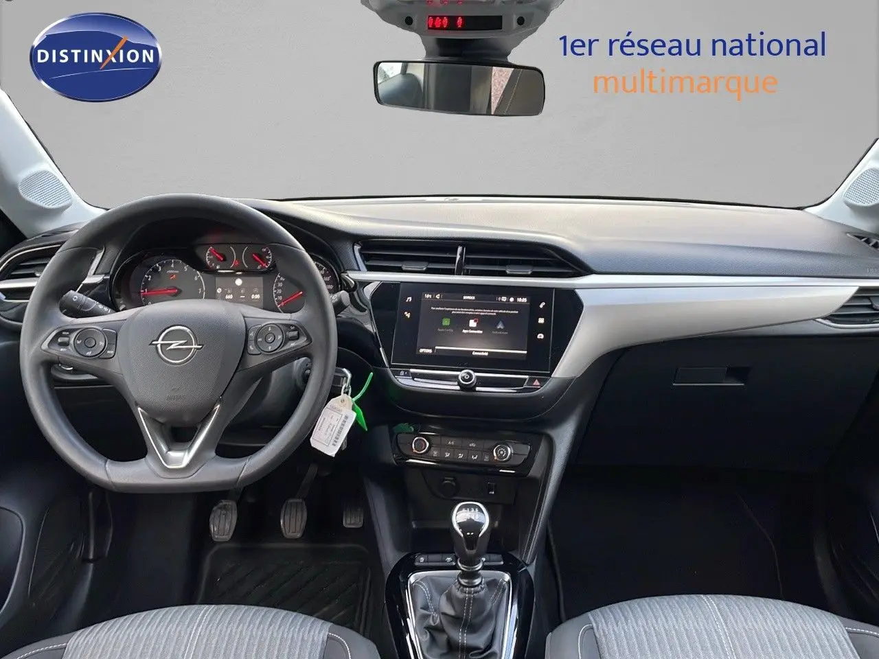 Vue intérieure avant de l'Opel Corsa 2022, tableau de bord noir et gris avec volant multifonction et levier de vitesse manuel.