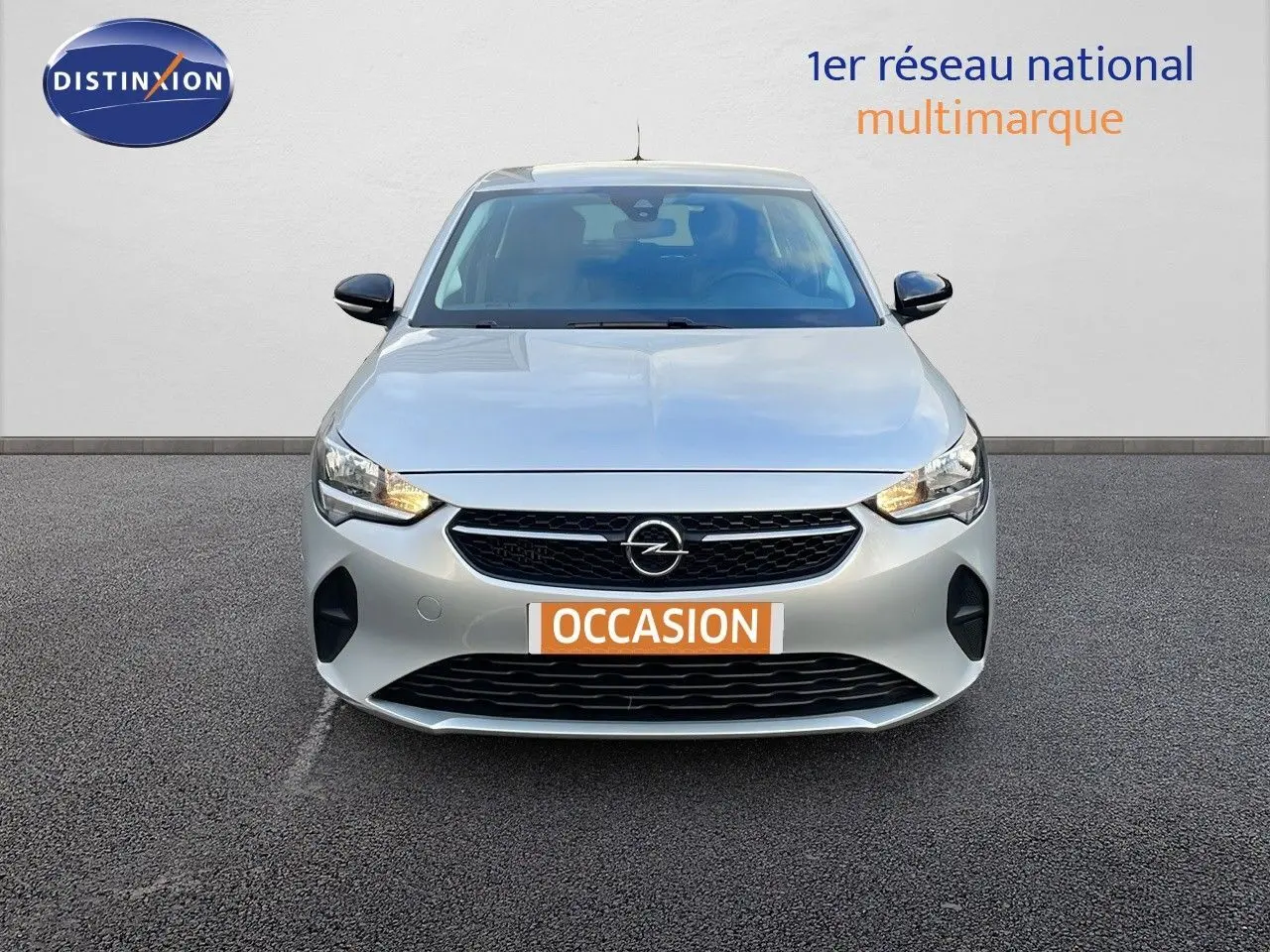 Vue frontale d'une Opel Corsa gris Kristall Metal de 2022 avec calandre noire et phares allumés.