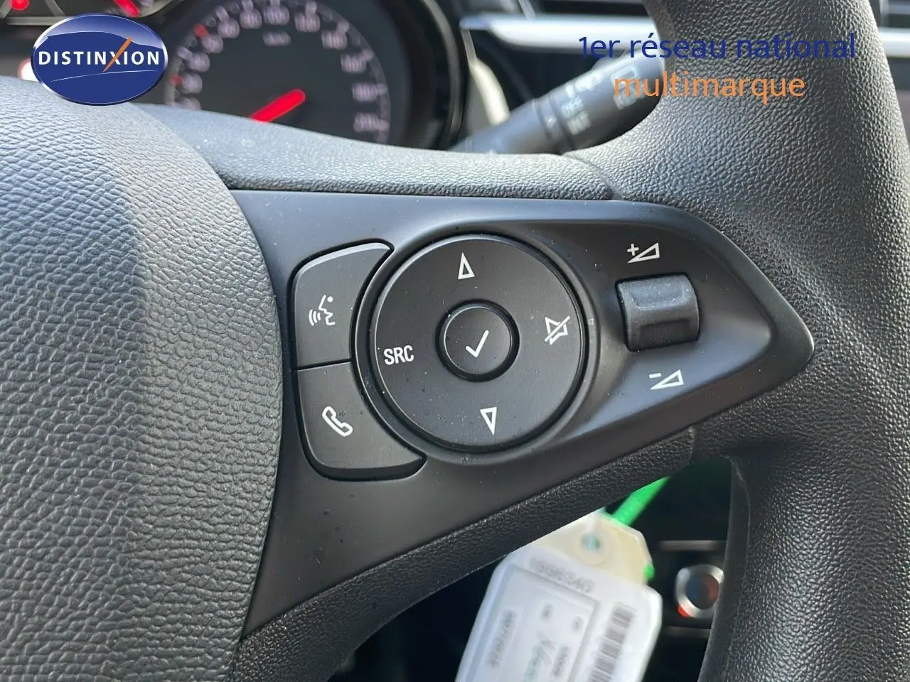 Gros plan sur les commandes multifonctions à gauche du volant en cuir noir d'une Opel Corsa gris Kristall Metal.