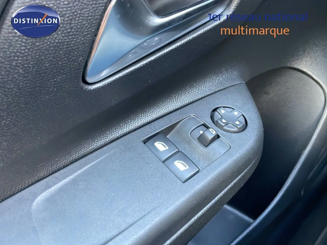 Gros plan sur les commandes de lève-vitres et réglage des rétroviseurs côté conducteur d'une Opel Corsa gris Kristall Metal.