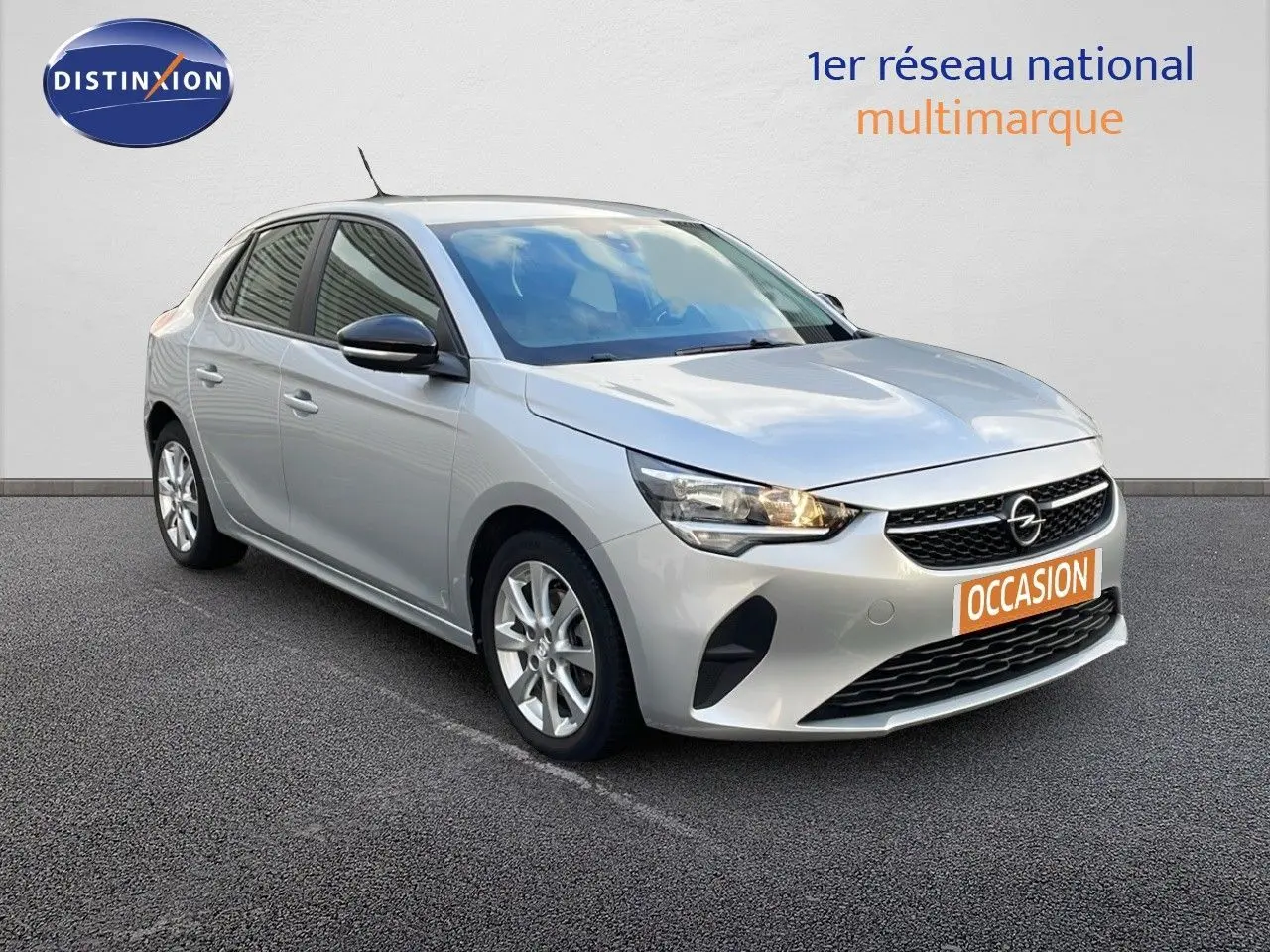Opel Corsa gris kristall metal vue 3/4 avant droit avec phares allumés sur fond neutre.