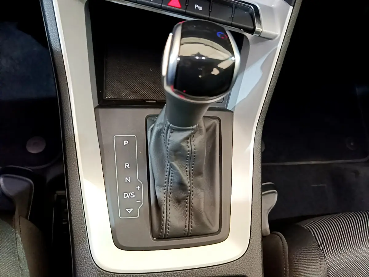 Le levier de vitesses automatique noir et chrome de l'Audi Q3 35 TDI 2021 vu de dessus, entouré de console grise.