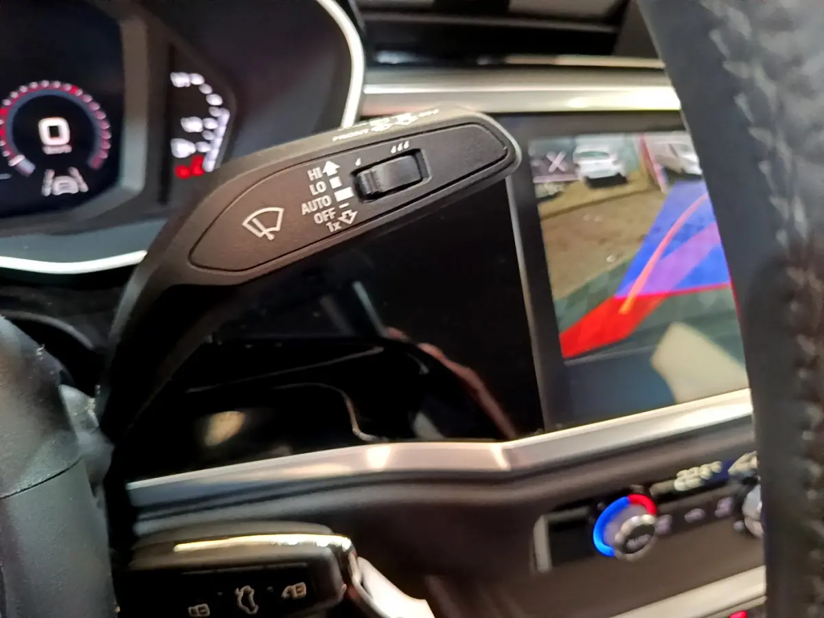 Gros plan sur la commande d'essuie-glace et l'écran de caméra de recul du tableau de bord d'un Audi Q3 noir.