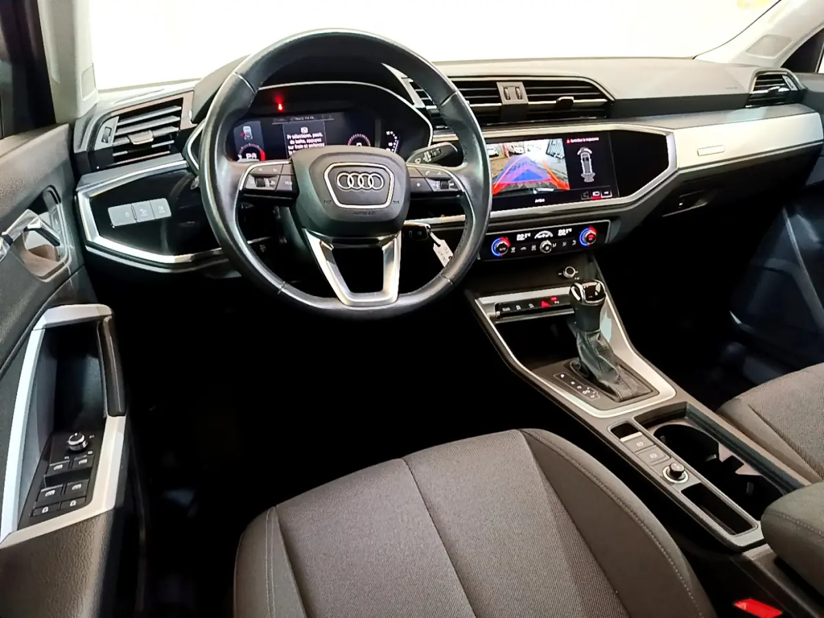 Vue intérieure de l'Audi Q3 35 TDI 2021, tableau de bord noir avec écran tactile et volant cuir multifonctions.