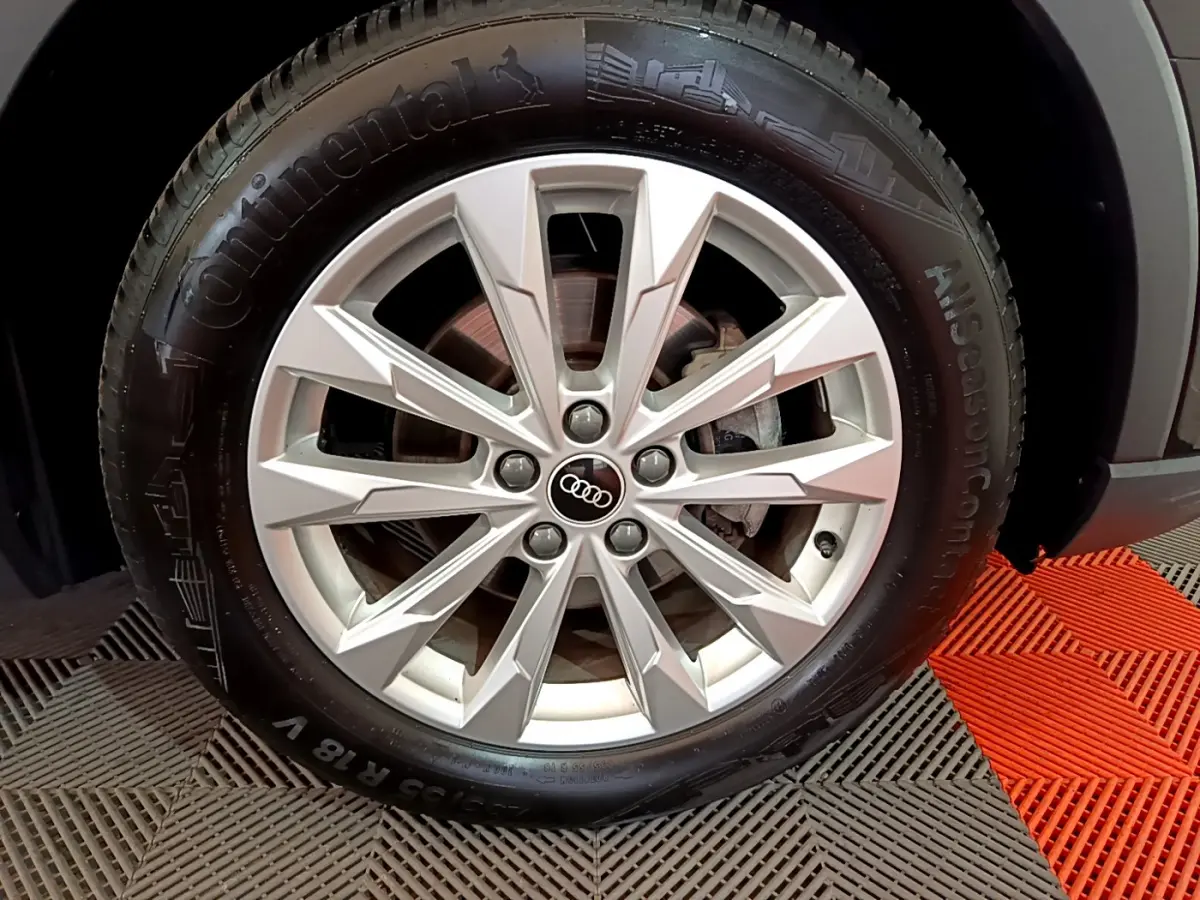 Gros plan sur la roue avant droite d'un Audi Q3 noir, mettant en valeur la jante argentée à design moderne.