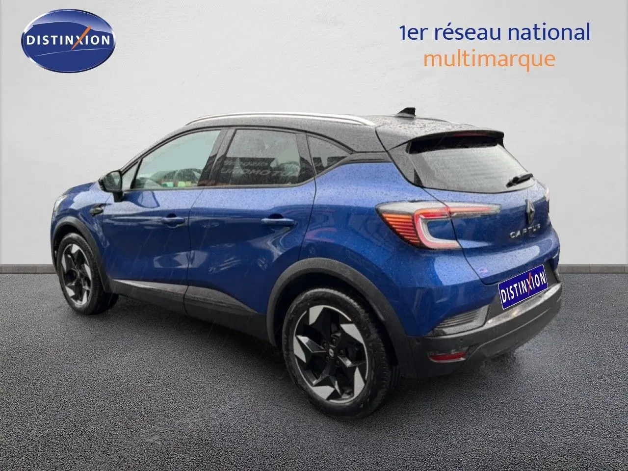 Vue 3/4 arrière droite d'un Renault Captur bleu Iron Metal avec toit noir et jantes noires distinctives.