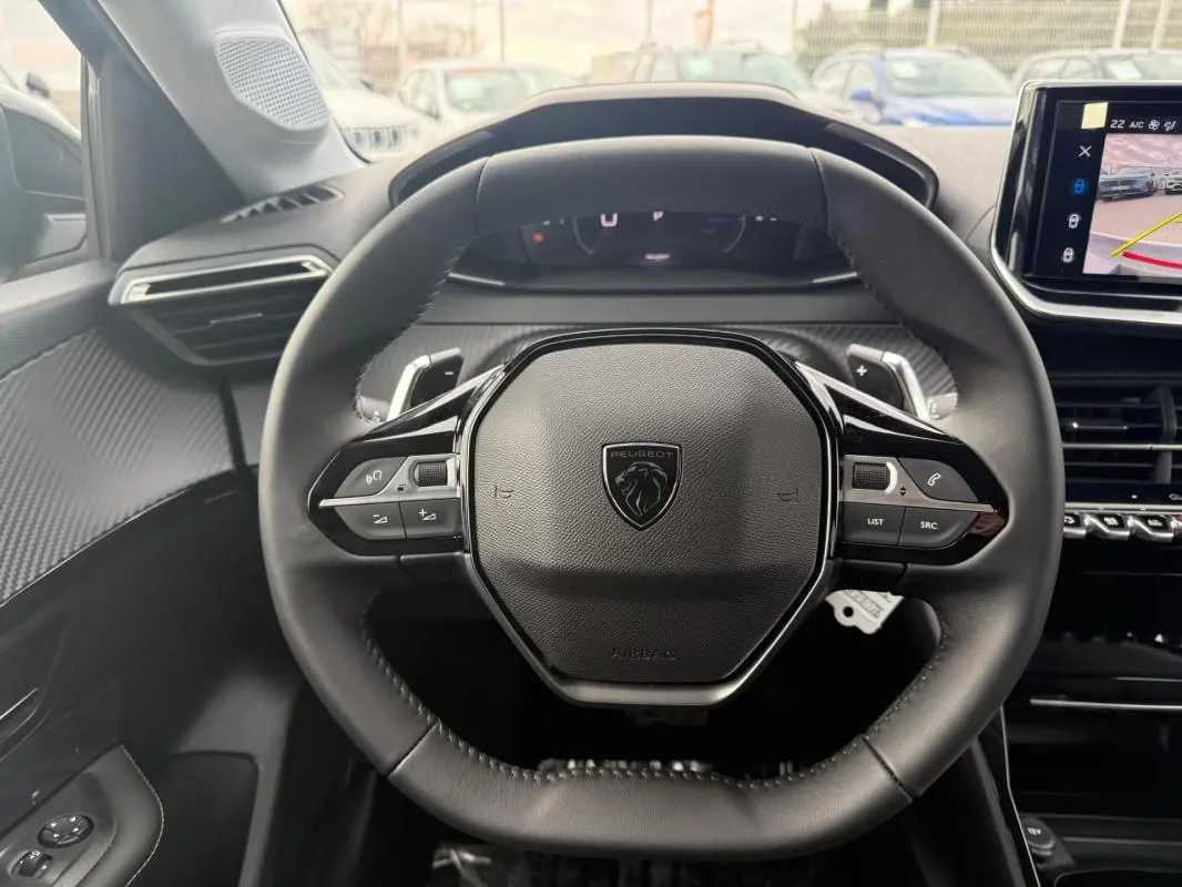 Vue centrée sur le volant noir du Peugeot 208 Hybrid 145 Allure 2025 avec tableau de bord et écran tactile visibles.