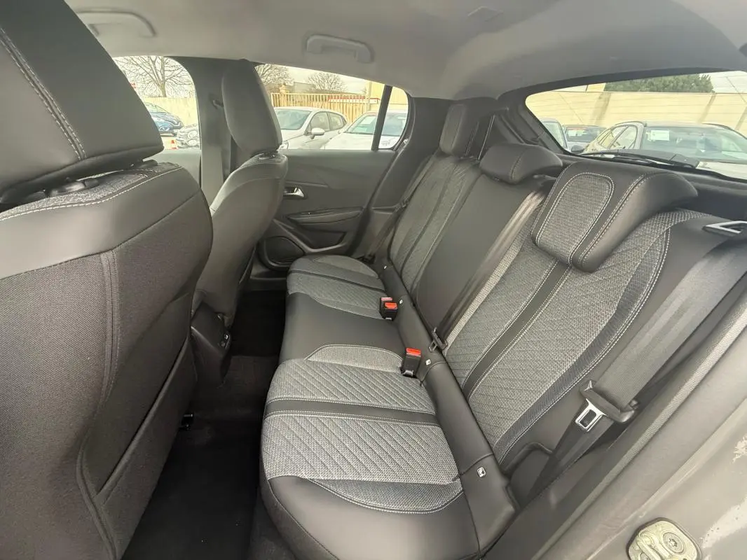 Vue intérieure arrière droite des sièges arrière gris avec sellerie mixte tissu et cuir de la Peugeot 208 Hybrid 145 Allure 2025.