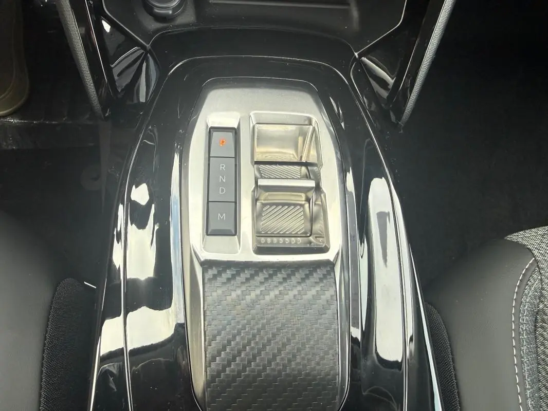 Vue rapprochée de la console centrale noire brillante avec sélecteur de vitesses automatique du Peugeot 208 Hybrid 145 gris.