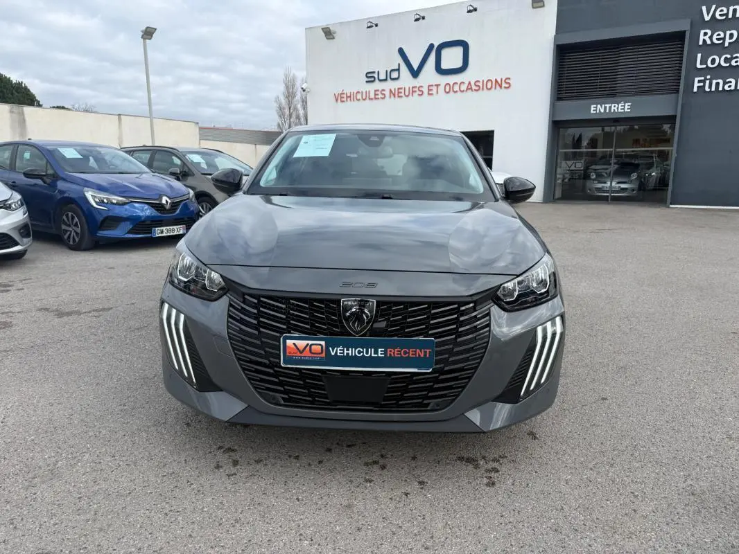 Vue avant d'une Peugeot 208 Hybrid 145 gris avec calandre noire et feux diurnes LED en griffes distinctives.