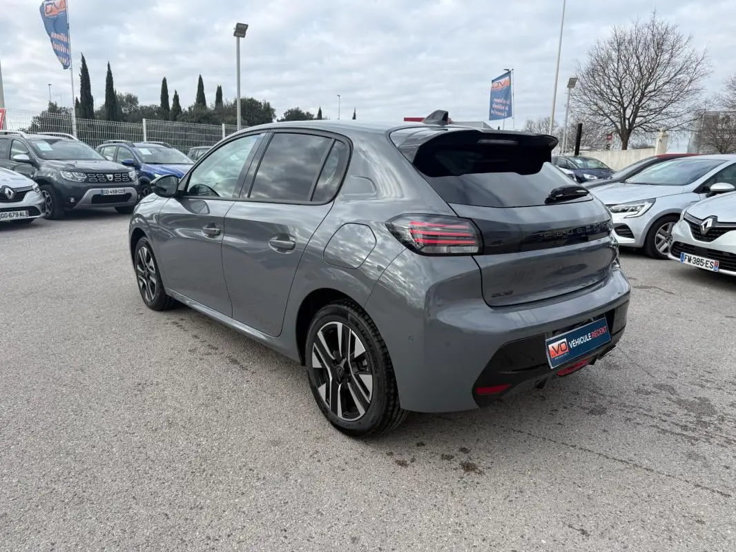 Peugeot 208 Hybrid gris vue 3/4 arrière droit, jantes alliage 16 pouces et antenne requin visible.