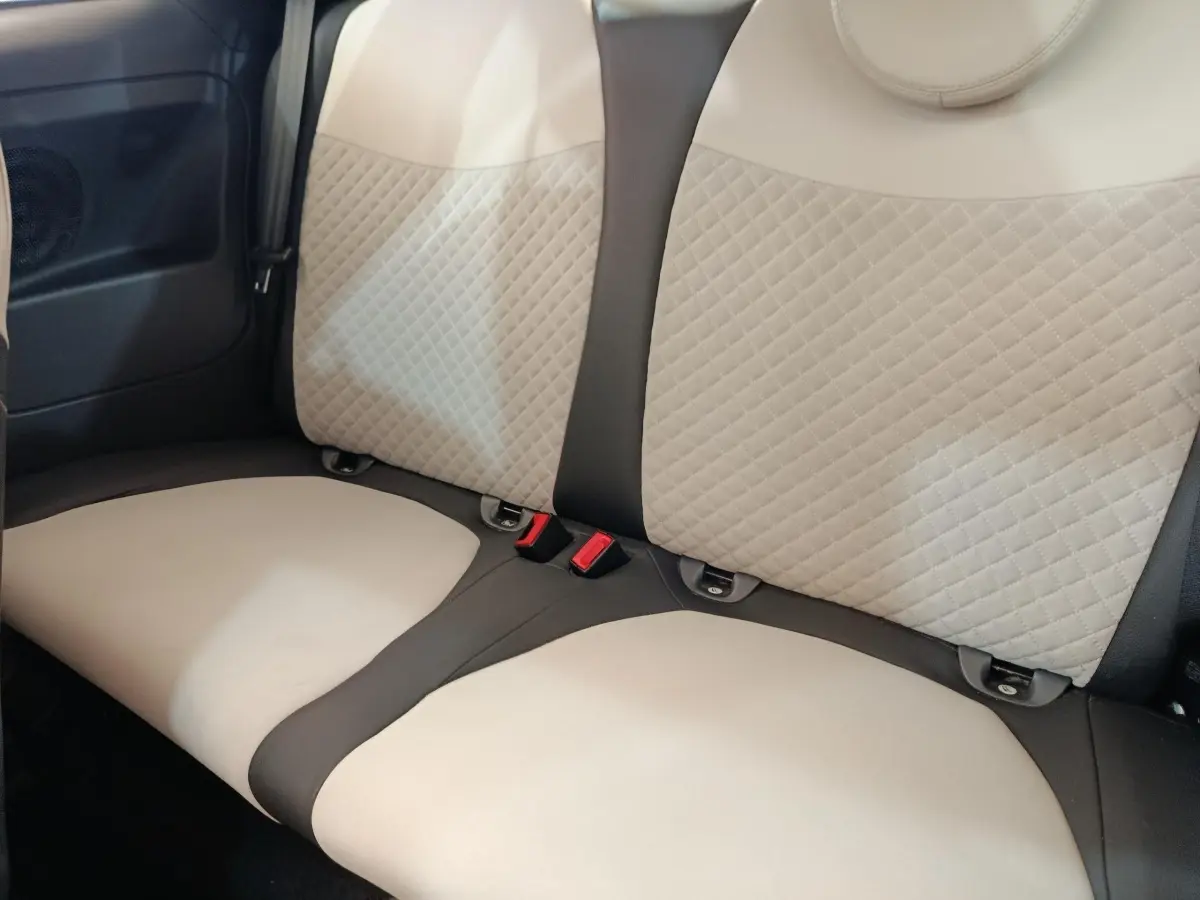 Vue rapprochée de la banquette arrière beige et noire de la Fiat 500 Hybrid Dolcevita 2022, avec ceintures visibles.
