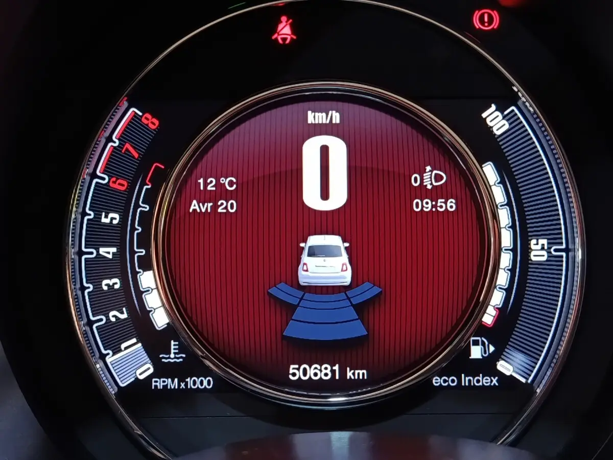 Vue rapprochée du tableau de bord numérique de la FIAT 500 blanche, affichant la vitesse à 0 km/h et l'indicateur de distance.