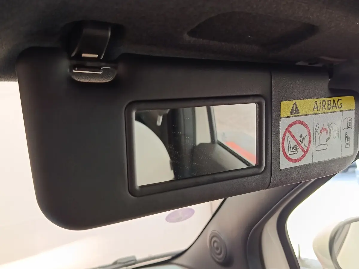 Miroir de courtoisie sur pare-soleil côté conducteur dans l’habitacle noir d’une Fiat 500 blanche.
