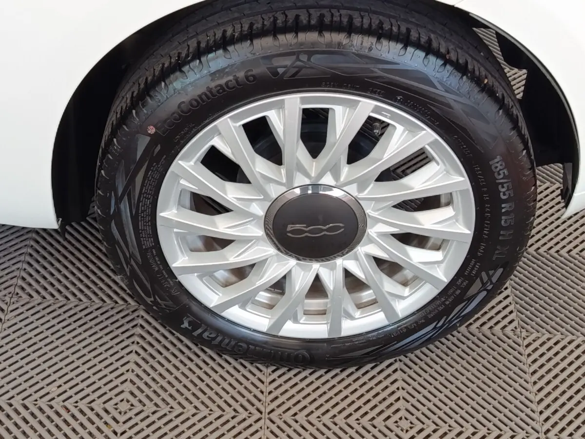 Gros plan sur la roue avant droite blanche d’une FIAT 500 Hybrid avec jante argentée et logo central noir.