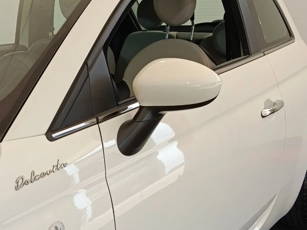 Gros plan sur la porte côté gauche blanche d'une Fiat 500 Dolcevita avec rétroviseur et logo distinctif.