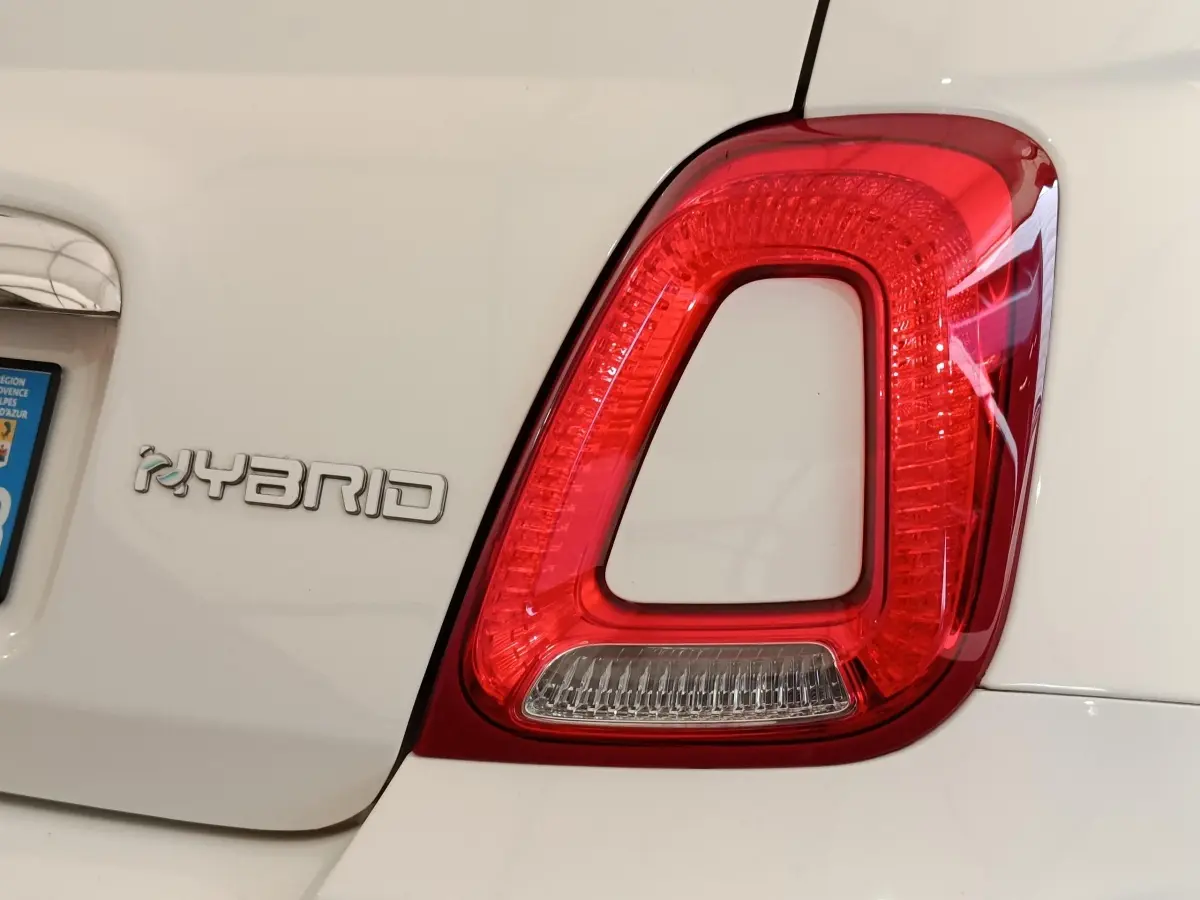 Gros plan sur le feu arrière droit rouge et le logo Hybrid sur la partie arrière blanche d’une Fiat 500 Dolcevita.