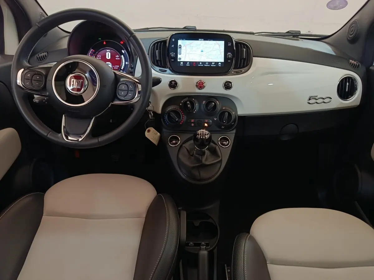 Vue intérieure frontale du tableau de bord blanc et volant cuir noir de la FIAT 500 Hybrid 2022 avec écran tactile central.
