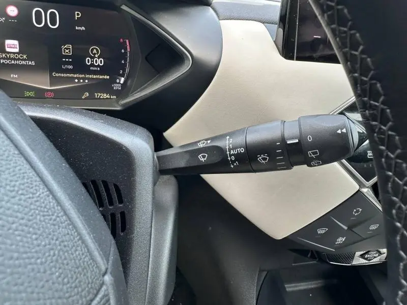 Détail du commodo d'essuie-glace à gauche du volant dans l'habitacle beige et noir du DS3 1.2 PureTech 2024.